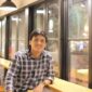 Seorang pria duduk di sebuah kafe modern di Bali, suasana santai ini kontras dengan perhatian publik atas kasus video bermuatan pornografi yang tengah viral dan menjadi sorotan hukum.  